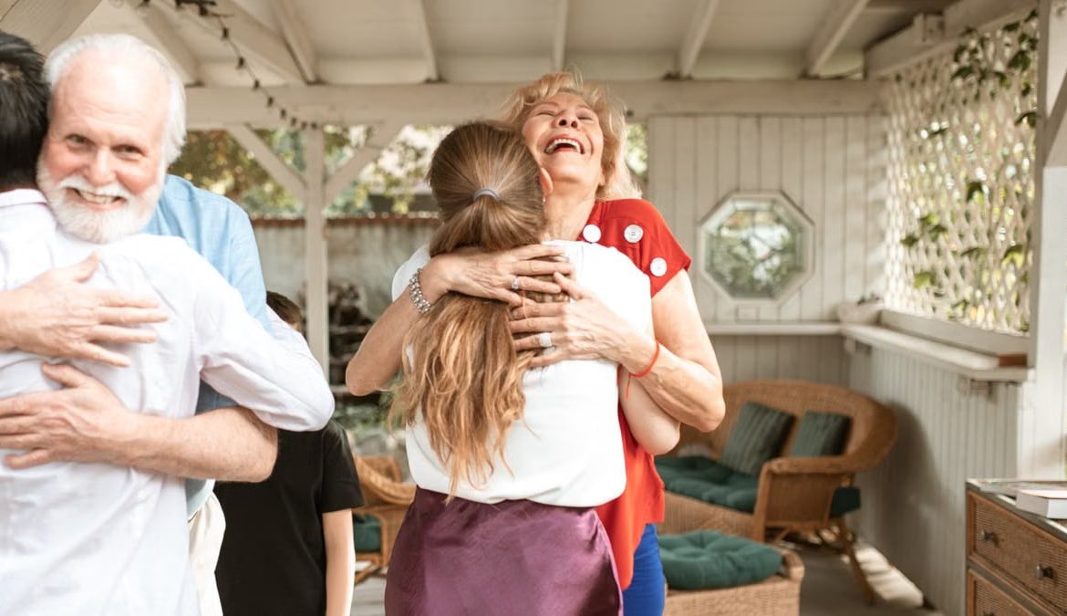 A heartwarming reunion with family members hugging and smiling in a cozy indoor setting.