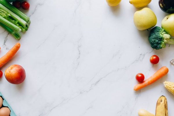 An assortment of fresh fruits and vegetables on a marble background, perfect for healthy lifestyle concepts.