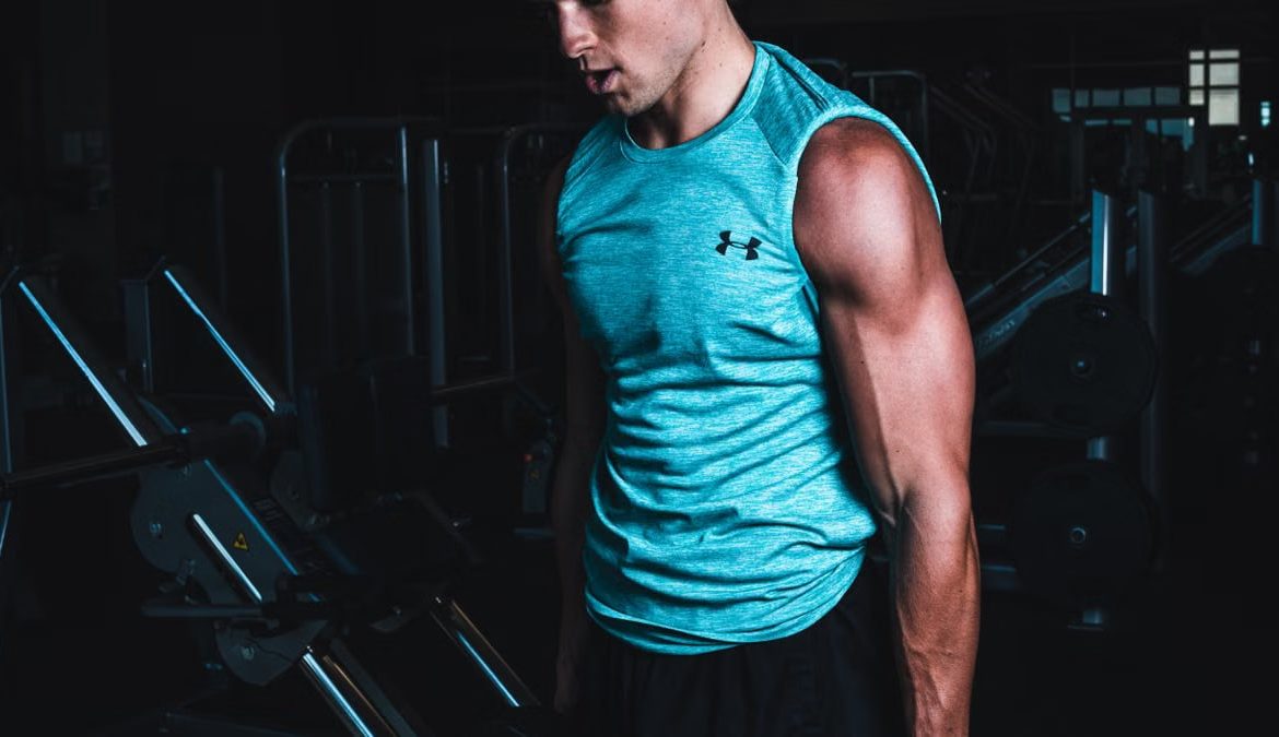 Man exercising indoors, lifting dumbbells for strength training in a Towson gym.