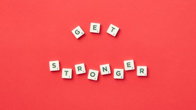 Motivational Scrabble letters form 'Get Stronger' on red backdrop for inspiration.
