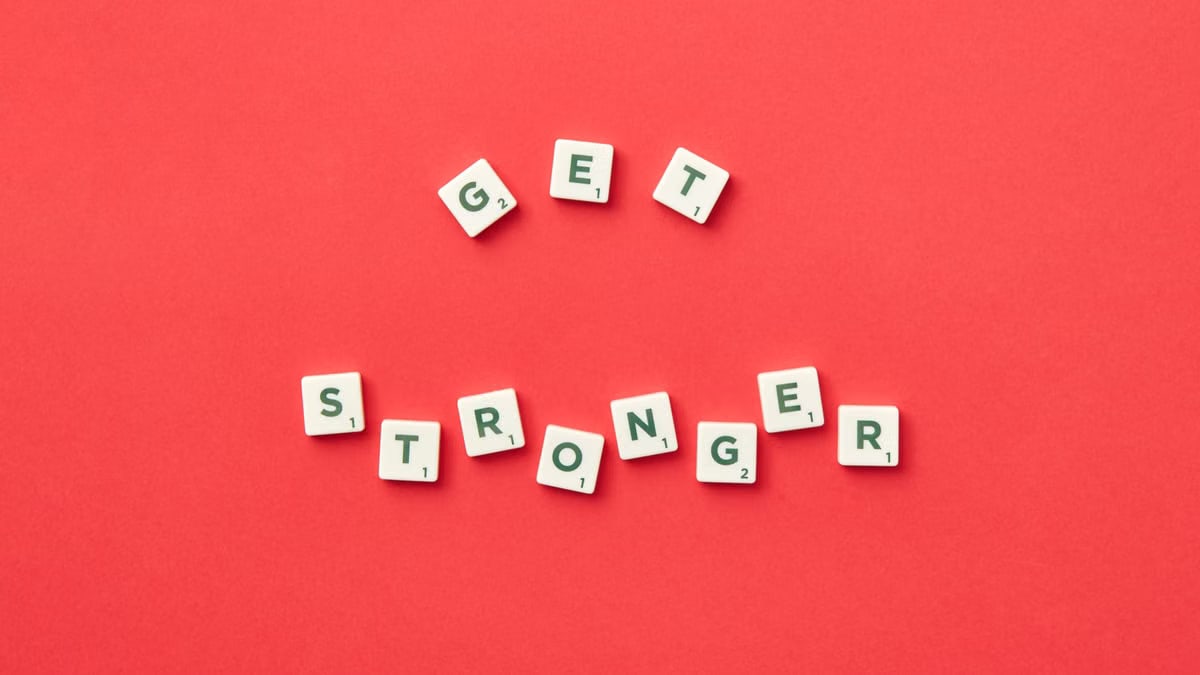 Motivational Scrabble letters form 'Get Stronger' on red backdrop for inspiration.